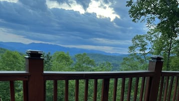 Un foyer extérieur installé sur une terrasse en bois, avec vue sur les montagnes et les arbres.