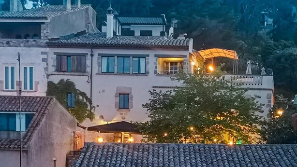 Un immeuble à plusieurs étages, doté d’un toit recouvert de tuiles, de nombreuses fenêtres et d’un balcon avec une balustrade.