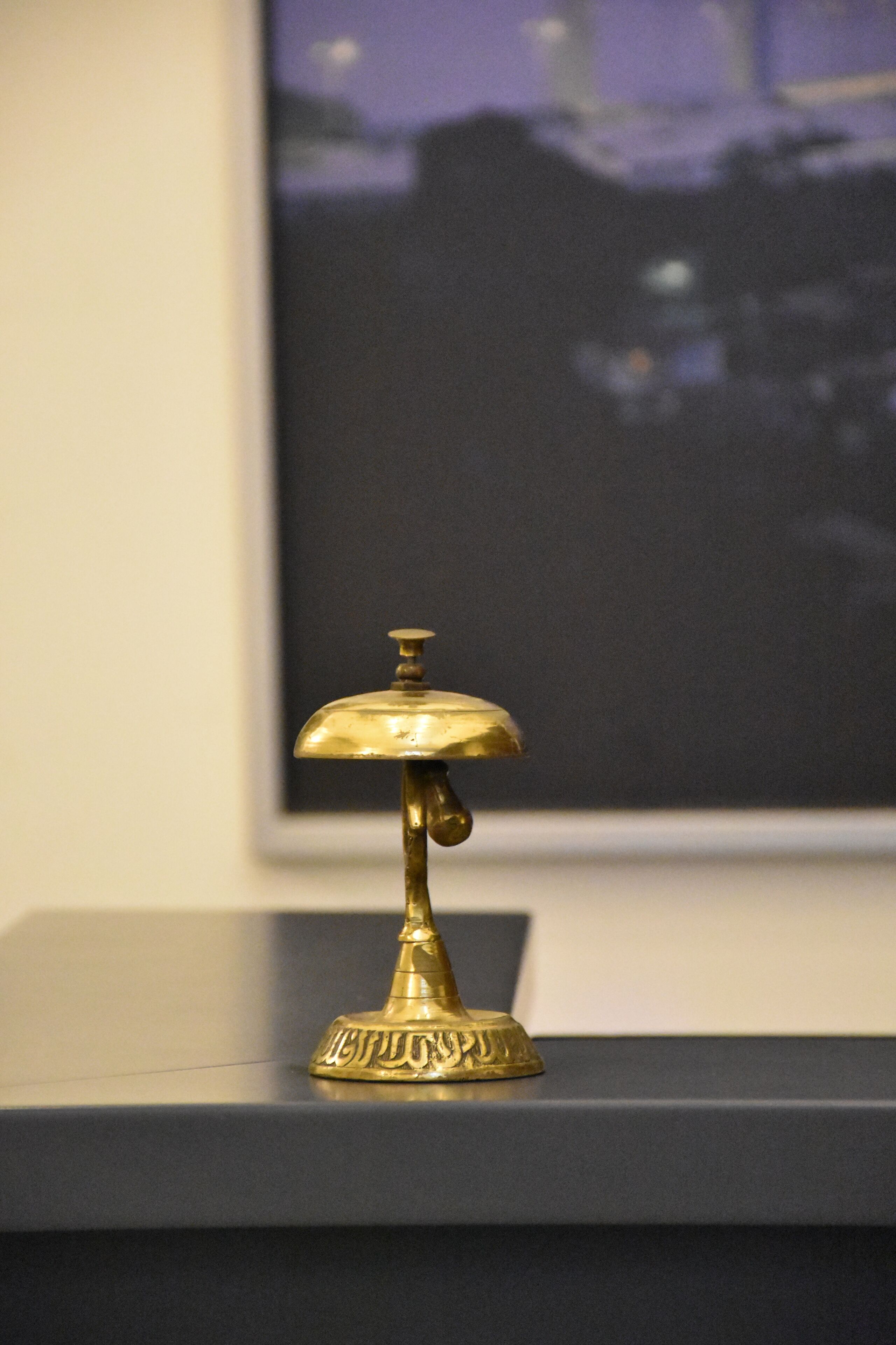 Una lámpara de bronce con una base decorativa sobre una superficie negra.