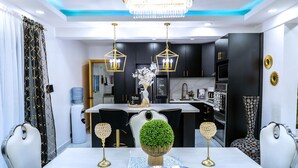A modern kitchen with black cabinets, a central island, and a dining area with a white table and chairs.