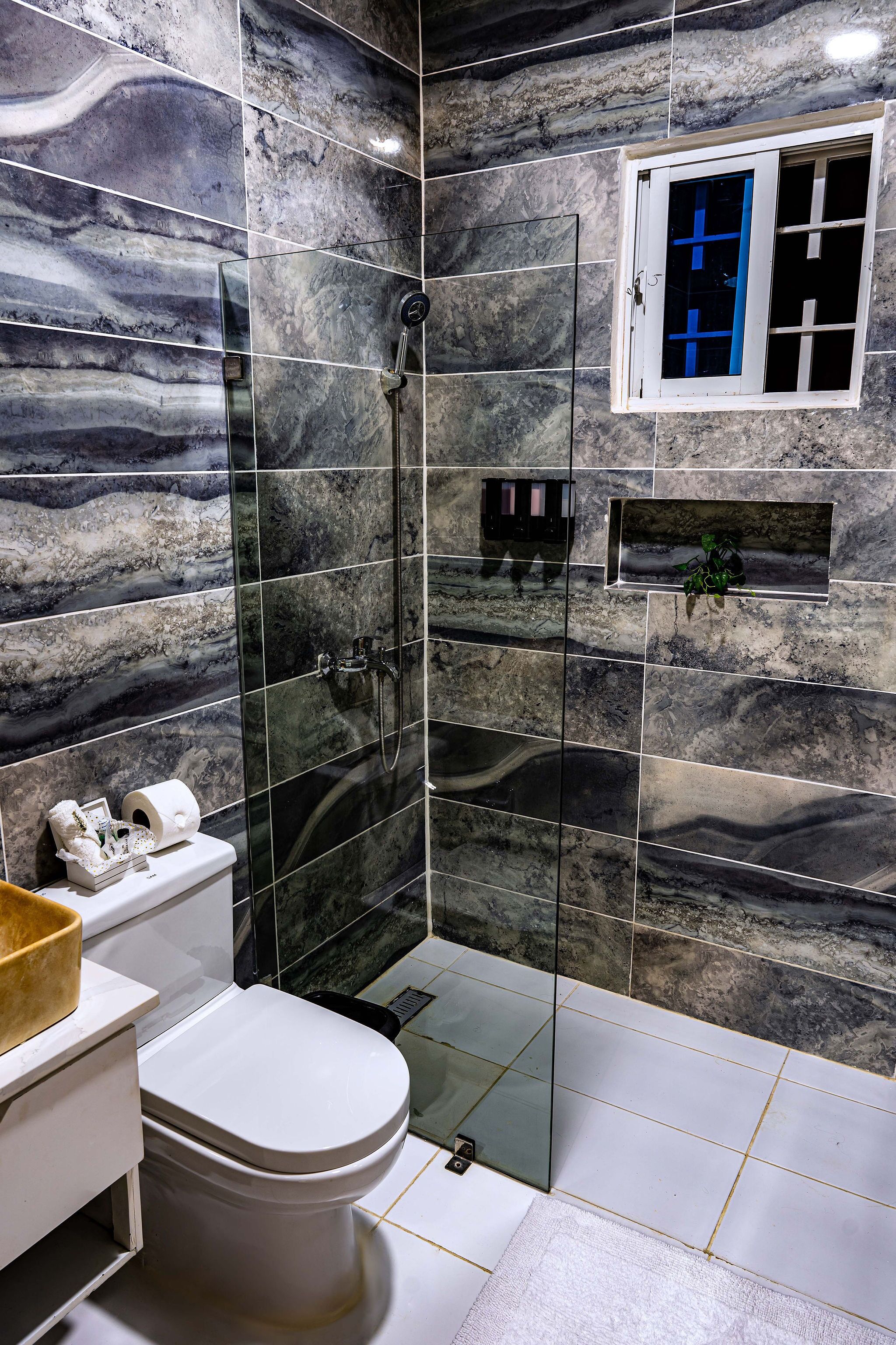 Une salle de bain avec une douche à parois de verre, des toilettes et un lavabo.
