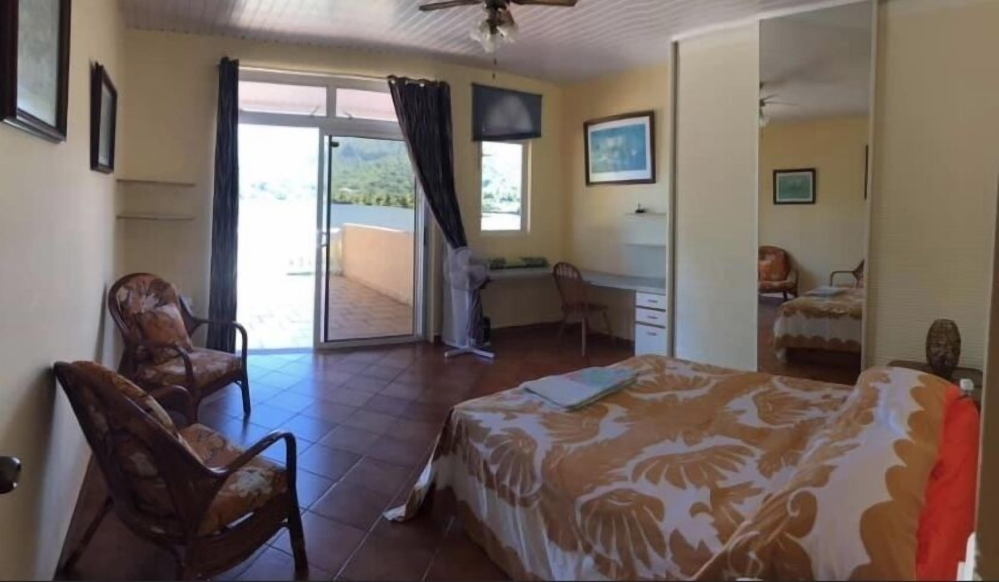 A hotel room with a bed, a desk, a chair, and a balcony with a view.