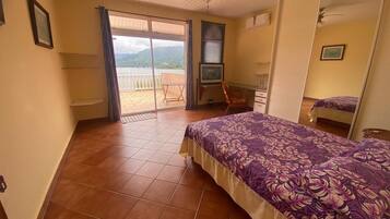 Un dormitorio con cama, escritorio, silla y vistas a un balcón.