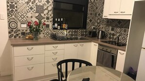 A modern kitchen with patterned backsplash, white cabinetry, and a round glass table with chairs. - Wisteria Place (Plympton)
