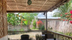 An outdoor patio with a woven ceiling, tables, and chairs. - The Backyard Inn (Moalboal)
