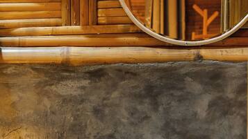 A bathroom with a wooden wall, a round mirror, a white sink, and a towel rack.