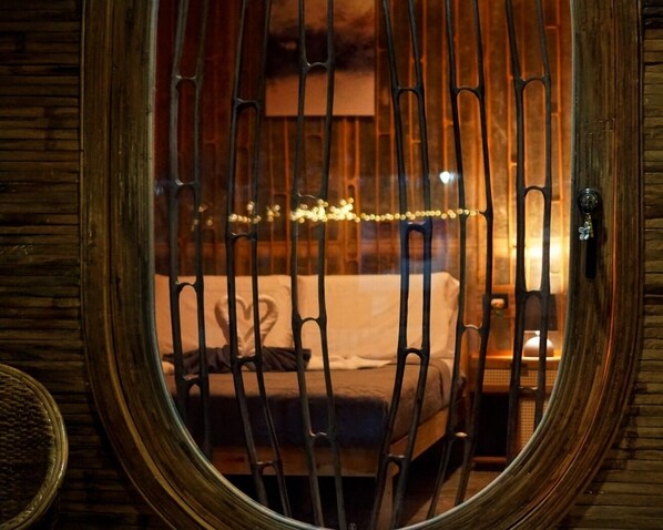 A room with a bed, a wooden door, and a window with a metal grille.