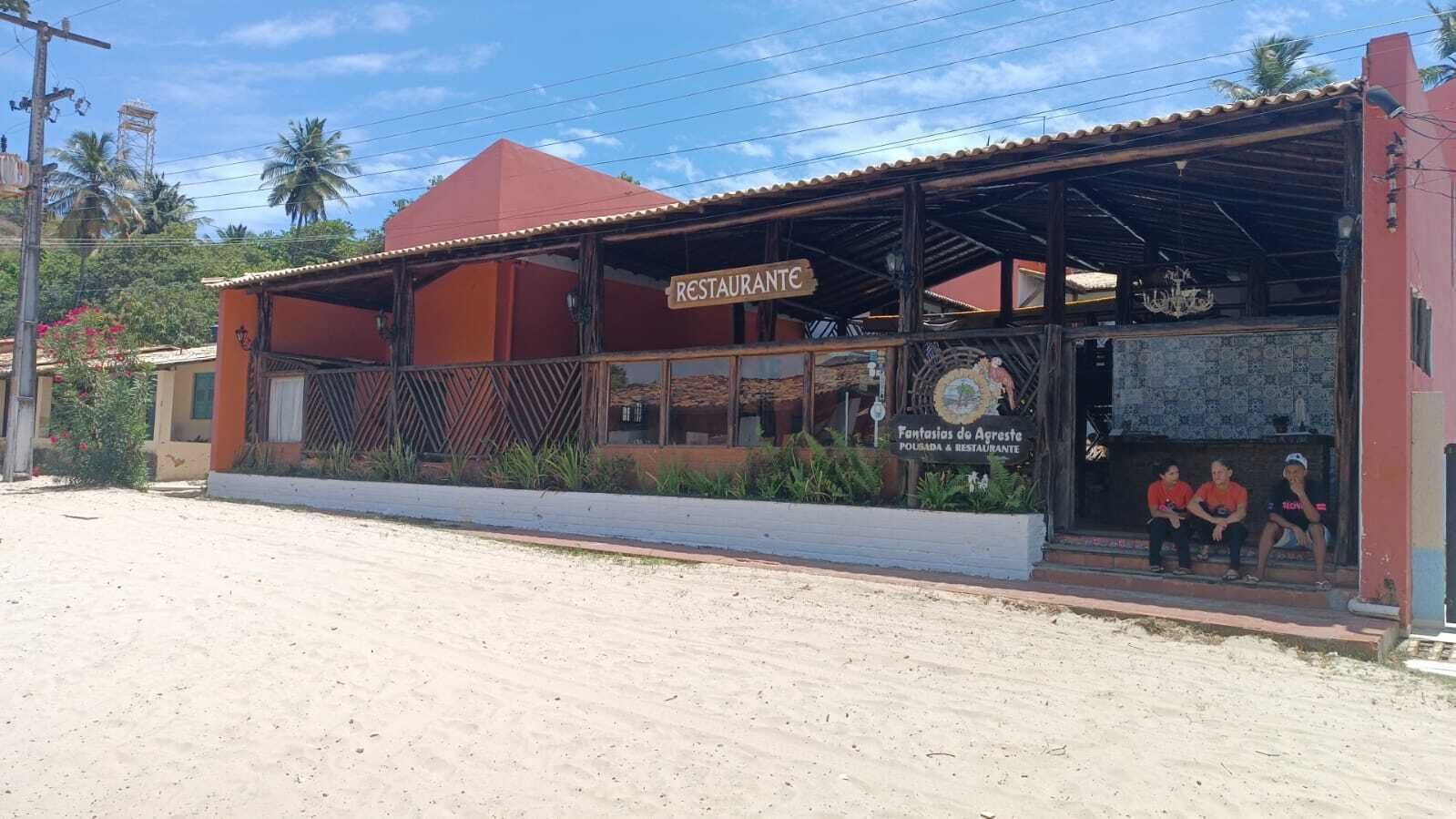 Restaurante com fachada vermelha e área externa coberta para clientes.