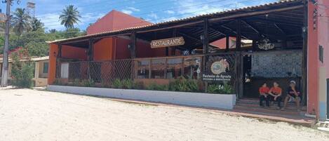 Restaurante com fachada vermelha e área externa coberta para clientes.