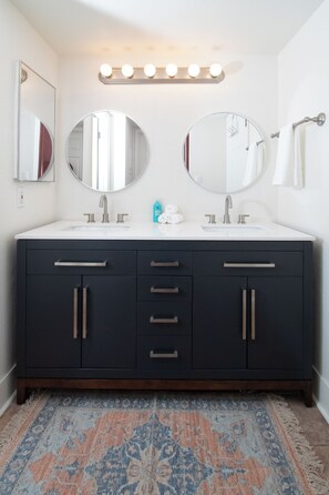 A modern bathroom with two sinks, a large mirror, and a vanity with drawers and cabinets. - Endless CASAbilities at this updated, clean Arcadia condo (Phoenix)