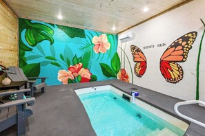 A spa room with a hot tub, a mural of flowers and butterflies, and a wooden ceiling.