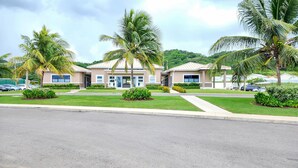 A modern hotel with a symmetrical facade, palm trees, and a well-maintained lawn. -  Ocean-Front Villa~ Beach, Pool, Tennis, 24hr security, Solar, WiFi, playground (Lucea)
