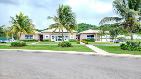 A modern hotel with a symmetrical facade, palm trees, and a well-maintained lawn.
