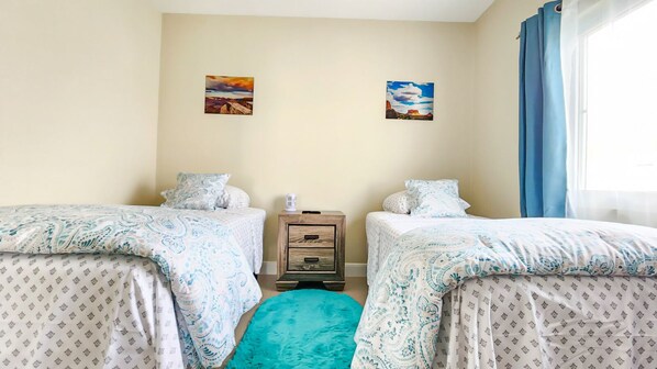 A bedroom with two beds, a nightstand, and a window with curtains. - Ocean-Front Villa~ Beach, Pool, Tennis, 24hr security, Solar, WiFi, playground (Lucea)