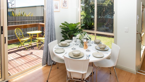 A dining area with a round table set for four, surrounded by white chairs. - Lacy's Place pet Friendly in the Town Center (Mallacoota)