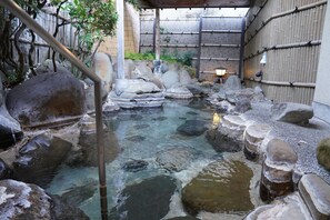 A traditional Japanese onsen with a clear hot spring, surrounded by rocks and a bamboo fence. - Shuzenji Kizuna Plus (Izu)