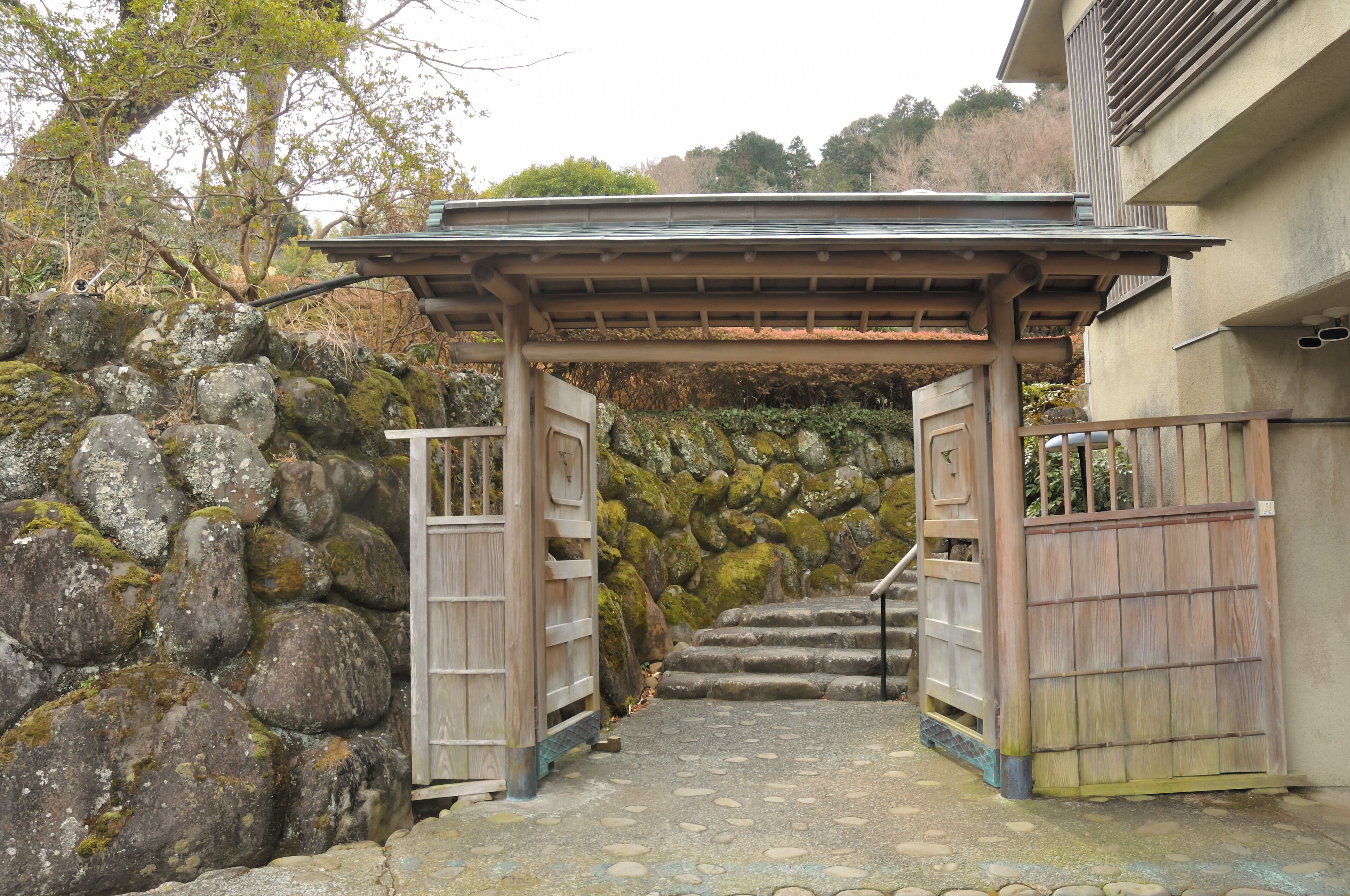 A traditional Japanese gate with a wooden structure and stone wall.