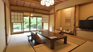 Een traditionele Japanse kamer met tatami vloerbedekking, een lage tafel en een televisie.