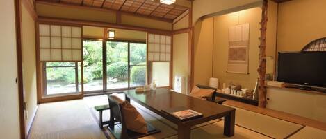 A traditional Japanese-style room with tatami flooring, a low table, and a television.