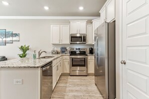 A modern kitchen with white cabinets, stainless steel appliances, and a granite countertop.