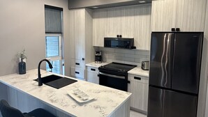 Una cocina moderna con una isla central, electrodomésticos de acero inoxidable y armarios de madera clara.
