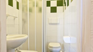 Une salle de bain avec douche, toilettes et lavabo.