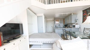 Een knus verblijf met een bed, een televisie, een eettafel en een keukenhoek.