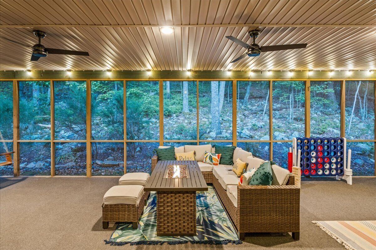 A cozy room with a large window, a sofa, a coffee table, and a ceiling fan.