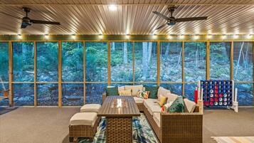 A cozy room with a large window, a sofa, a coffee table, and a ceiling fan.
