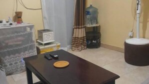 A living room with a dark wooden coffee table, a white fan, and a water dispenser. - Habesha circle (kampala)