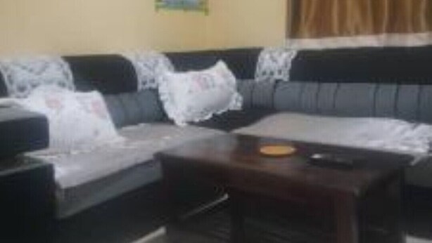A living room with a sofa, a coffee table, and a wall with a colorful poster. - Habesha circle (kampala)