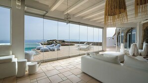 Ein moderner, großzügiger Lounge-Bereich mit einer großen Glaswand, die Meerblick und ferne Berge bietet.