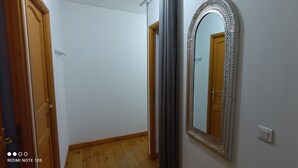 Un pasillo con una puerta de madera, un espejo con un marco decorativo y un interruptor de luz en la pared.