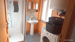 Un baño con ducha, lavamanos y lavadora.