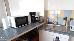 Una cocina equipada con microondas, cafetera y lavabo.