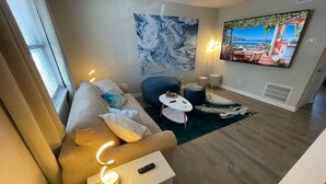 Una sala de estar moderna con un sofá, una mesa de centro, un televisor y un cuadro en la pared.