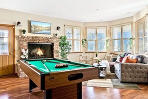 Relax by the fireplace and enjoy a game of pool in this inviting living room with a comfortable sofa and seating area.