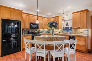 Enjoy cooking in this well-equipped kitchen with a central island, stove, microwave, and refrigerator.