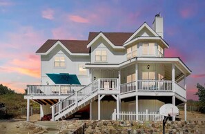Stunning two-story residence with a spacious balcony and central staircase, set amidst a serene natural backdrop.