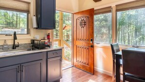 Uma cozinha com armários escuros, uma porta de madeira e um espaço de refeições com mesa e cadeiras.