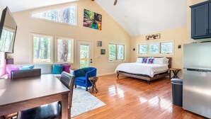 Quarto espaçoso com uma cama grande, uma mesa de jantar e várias janelas que proporcionam luz natural.