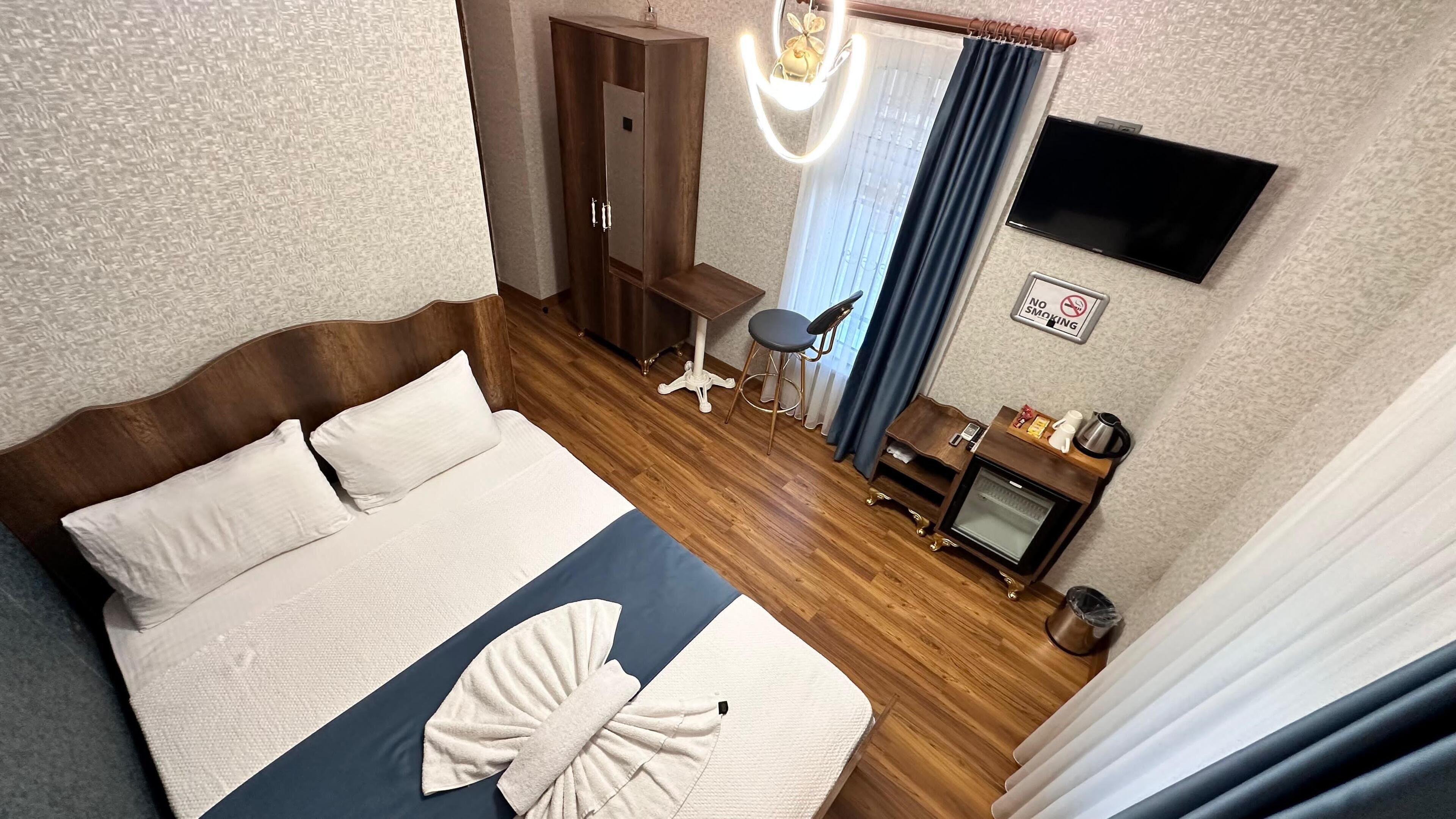 A hotel room with a large bed, a desk with a chair, a TV, and a small table with a chair.