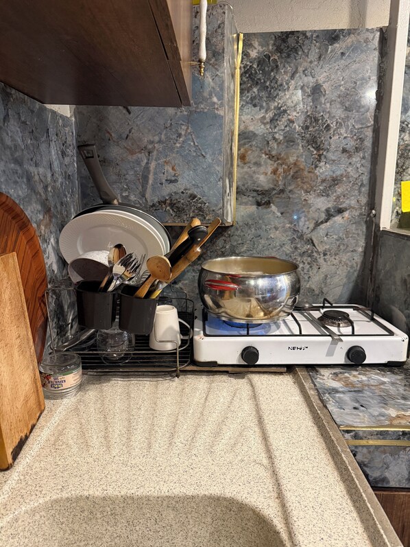 Une cuisine équipée d’une cuisinière à gaz, avec une casserole sur le brûleur, ainsi que divers ustensiles et ustensiles de cuisine.