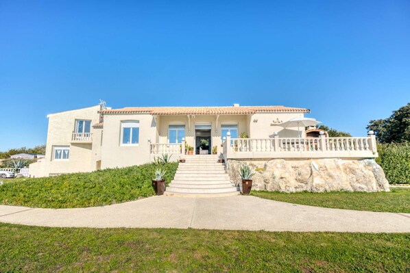 A two-story house with a tiled roof, a front porch, and a stone retaining wall. - La Villa du Chay - Exceptional villa (Angoulins)