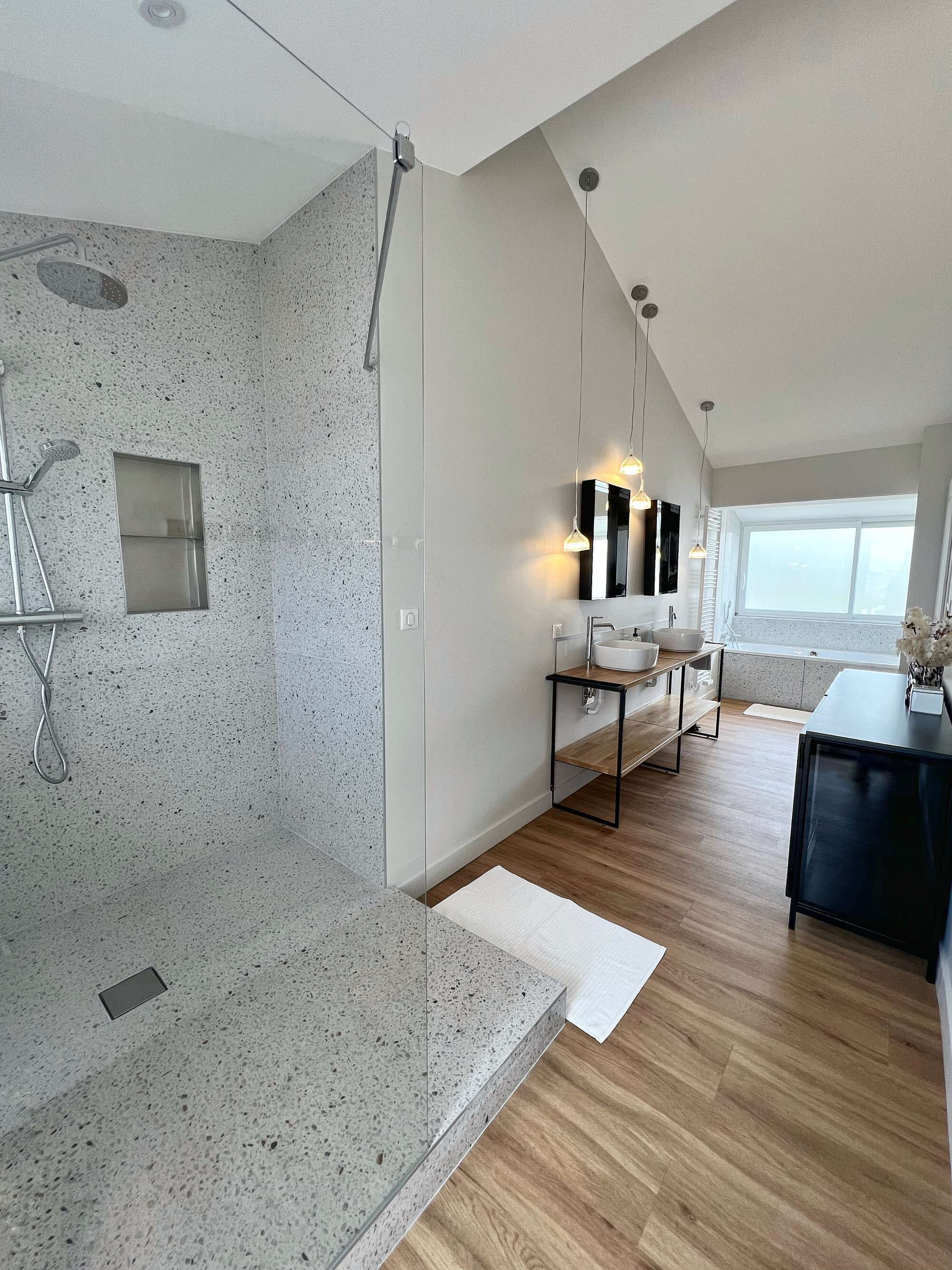 Un baño moderno con ducha, lavamanos y tocador.