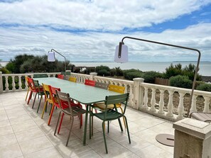 An outdoor dining area with a table and chairs, overlooking a body of water. - La Villa du Chay - Exceptional villa (Angoulins)