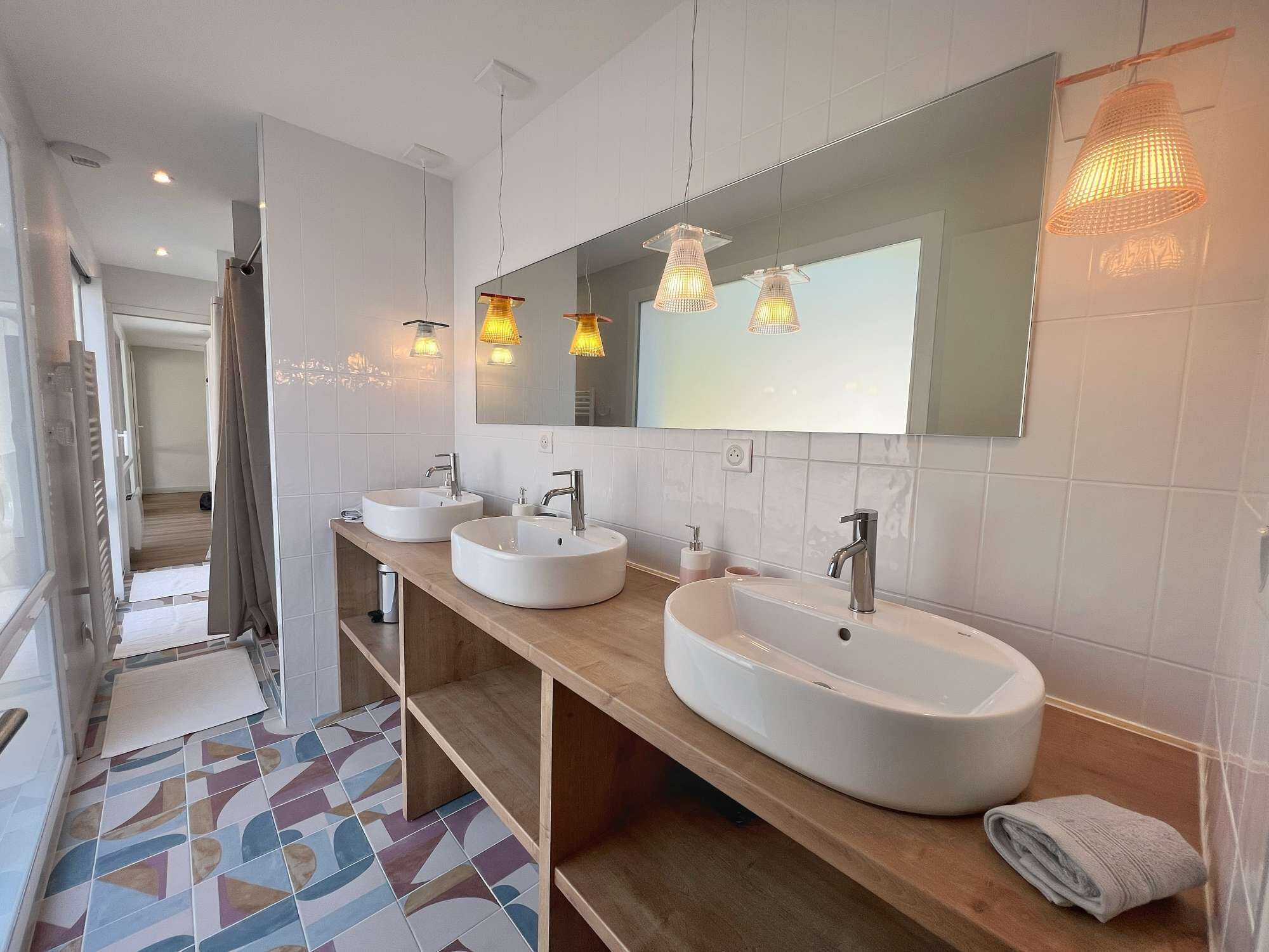 A modern bathroom with two white sinks, a large mirror, and a wooden vanity.