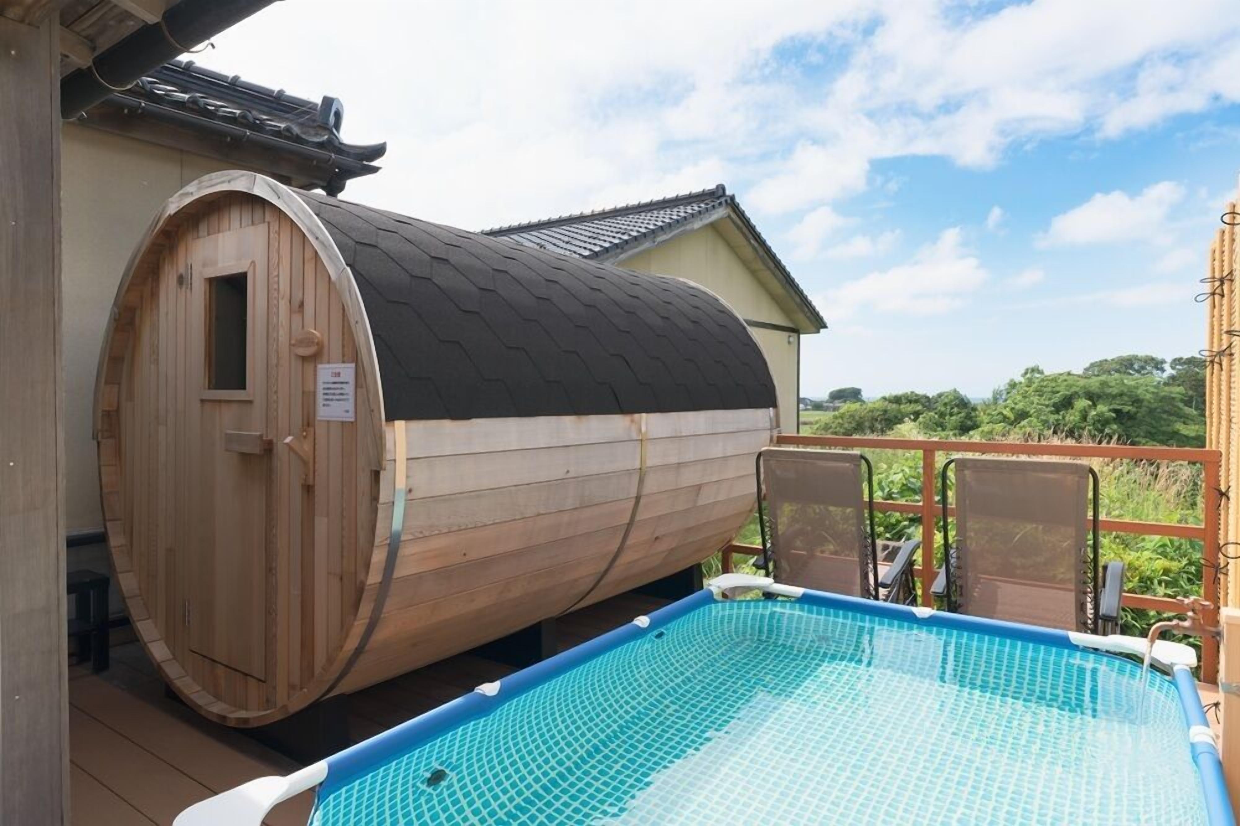 Un sauna en bois situé à côté d’une piscine, avec vue sur la verdure.