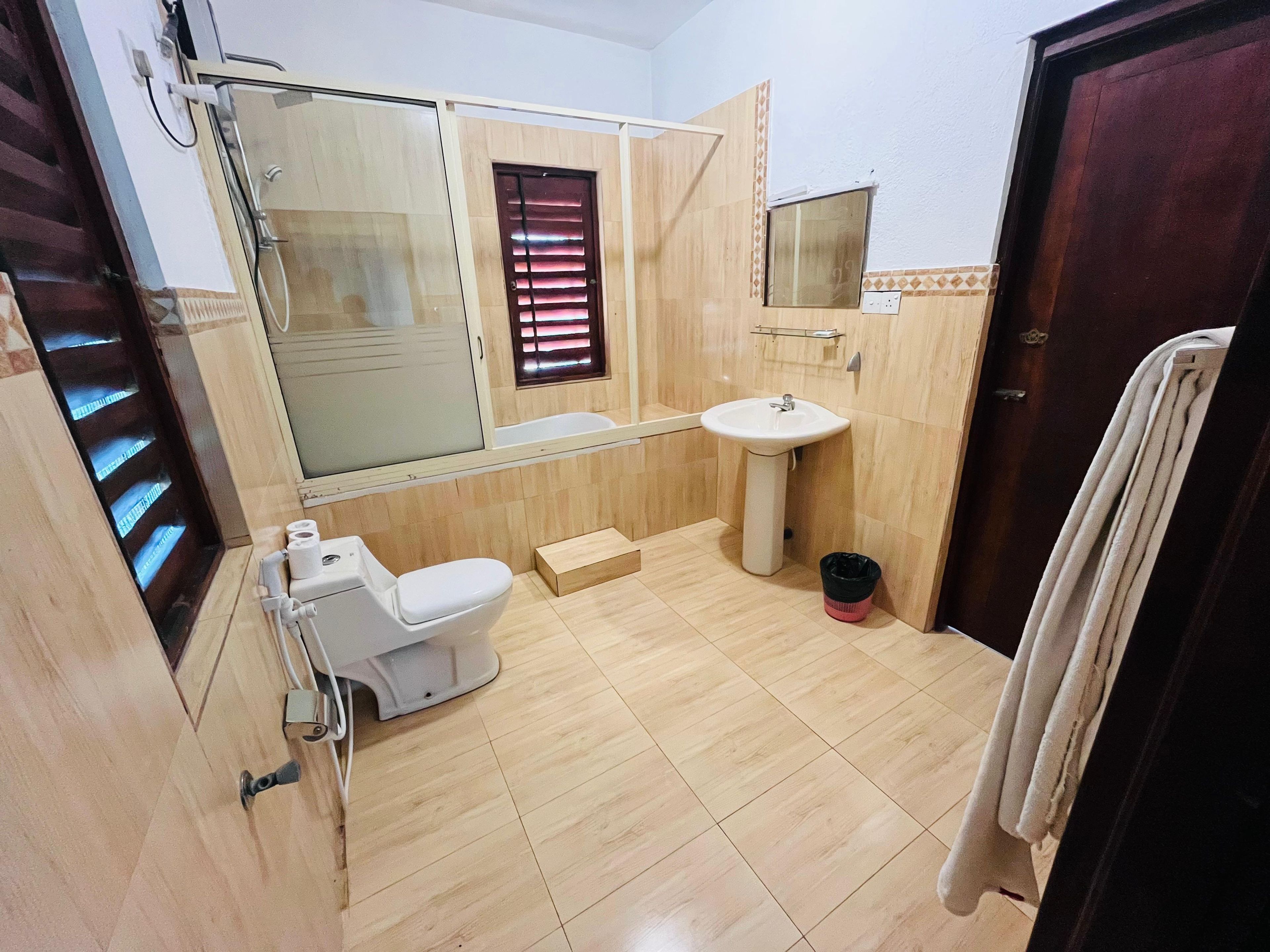 Un baño con inodoro, lavamanos y zona de ducha.
