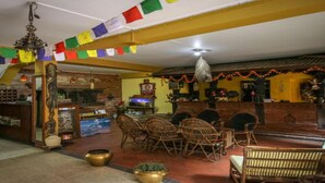 A traditional room with a reception desk, wicker chairs, and a decorative altar. - MeroStay 155 GGH (Bhaktapur)